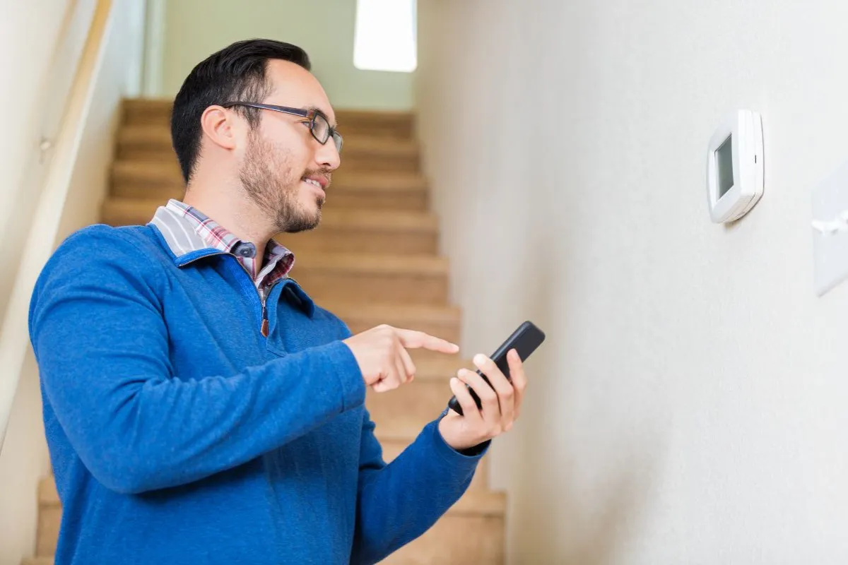P1-meter uitlezen via smartphone-app terwijl persoon bij slimme meter aan de muur staat in huis.